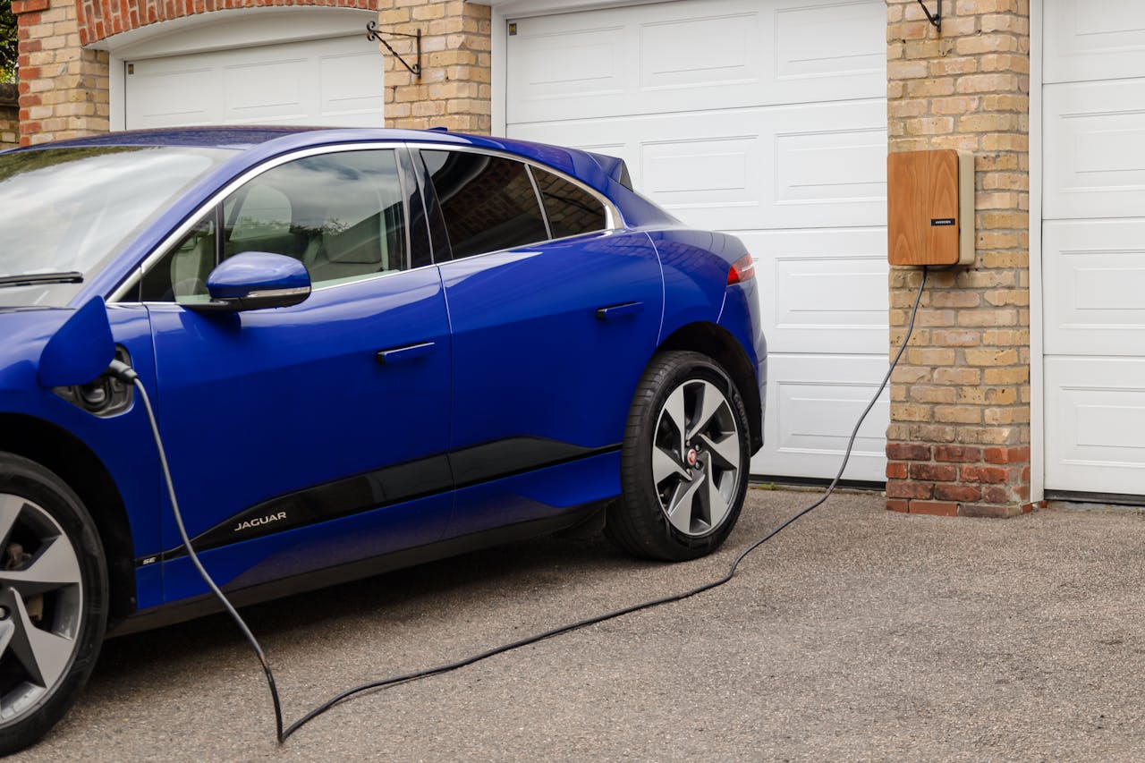 heros-img Blue electric vehicle charging at home using wall-mounted unit. Sustainable transportation solution.