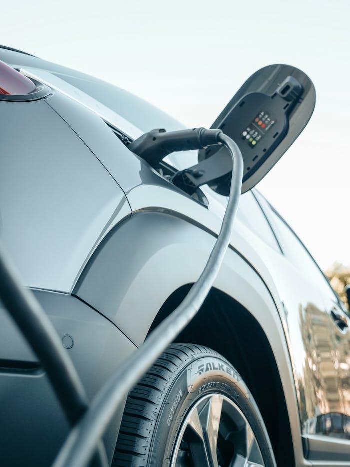 who-we-are Detailed view of an electric car plugged into a charging station outdoors.
